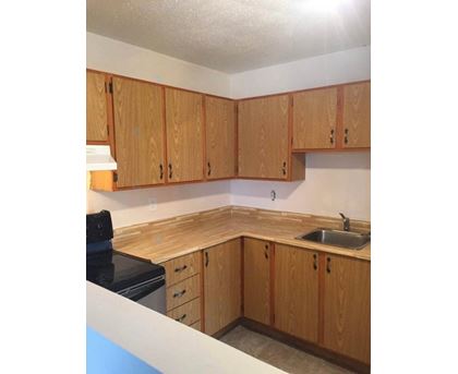 A kitchen with wooden cabinets and a black stove top.