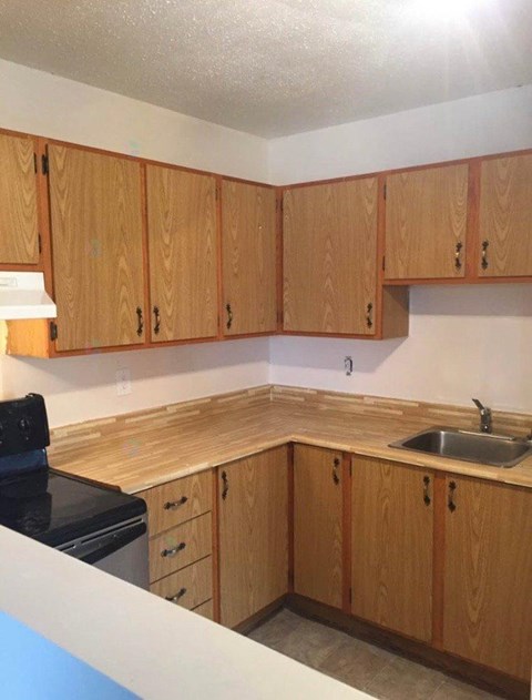 A kitchen with wooden cabinets and a black stove top.
