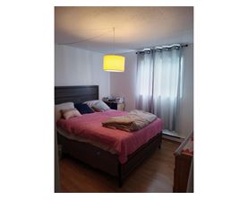 A bedroom with a bed, nightstand, and lamp.