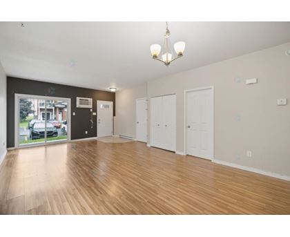 A spacious room with wooden flooring and white walls.