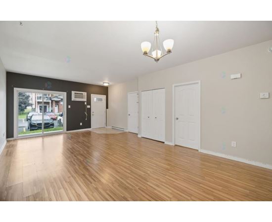 A spacious room with wooden flooring and white walls.