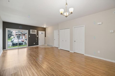 A spacious room with wooden flooring and white walls.