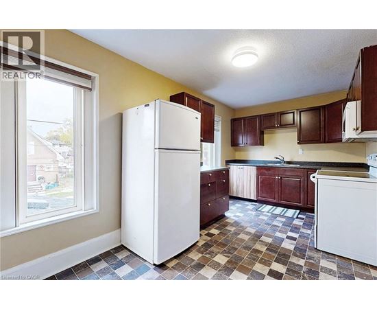A kitchen with a white refrigerator and brown cabinets.