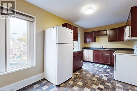 A kitchen with a white refrigerator and brown cabinets.