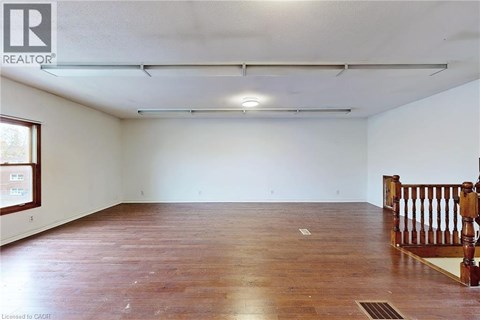 A spacious room with wooden flooring and white walls.