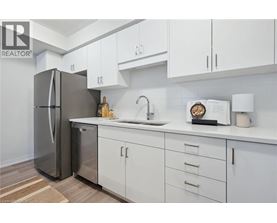 A modern kitchen with white cabinets and a stainless steel refrigerator.
