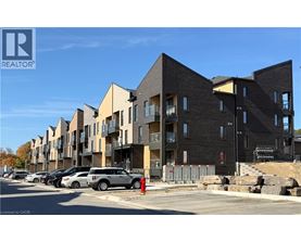 A row of modern apartment buildings with cars parked in front.