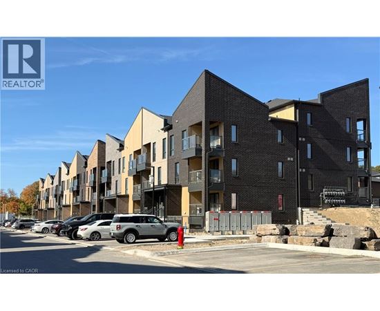 A row of modern apartment buildings with cars parked in front.