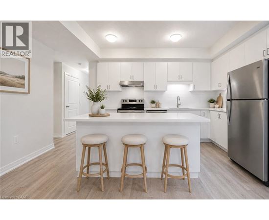 A kitchen with white cabinets and a white island with a refrigerator on the right.