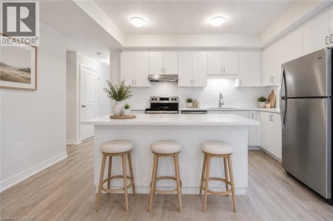 A kitchen with white cabinets and a white island with a refrigerator on the right.