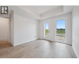 A spacious room with a door leading to a balcony with a view of a field.