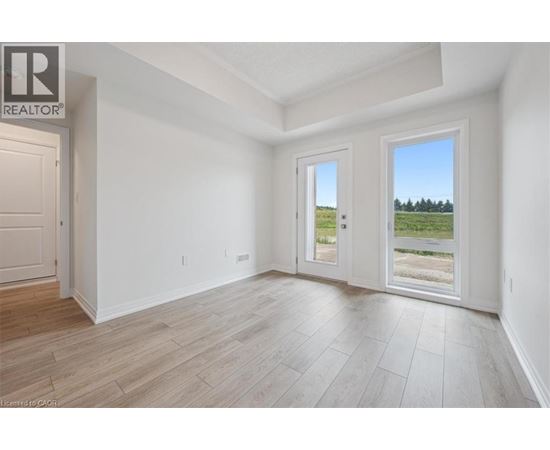 A spacious room with a door leading to a balcony with a view of a field.