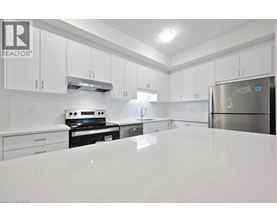 A white kitchen with a refrigerator on the right.