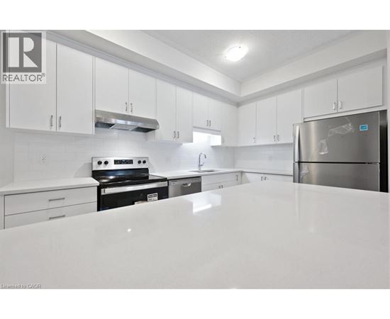 A white kitchen with a refrigerator on the right.