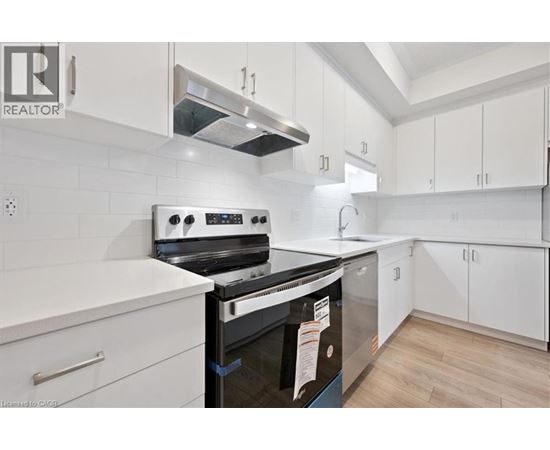 A modern kitchen with white cabinets and a black stove top oven.
