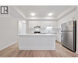 A white kitchen with a refrigerator on the right.