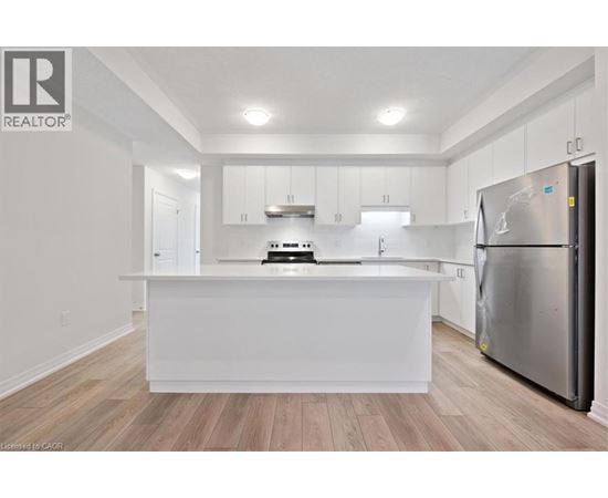 A white kitchen with a refrigerator on the right.