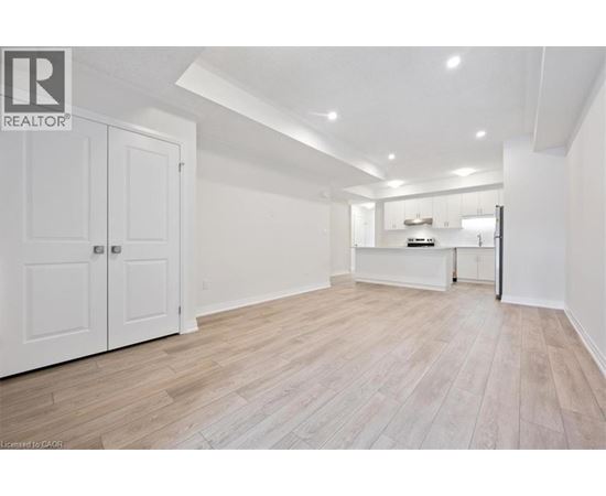A spacious room with wooden flooring and white walls.