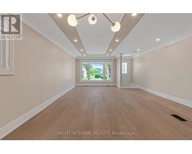A spacious room with wooden flooring and a large window.