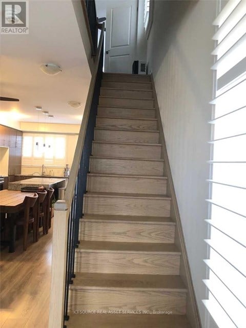 A wooden staircase with a black railing.