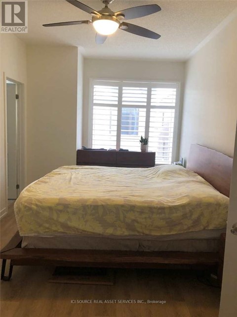 A bedroom with a bed, a ceiling fan, and a window with blinds.