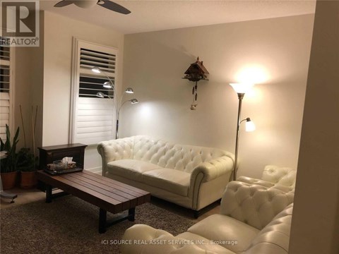 A white tufted couch sits in a living room with a wooden coffee table in front of it.