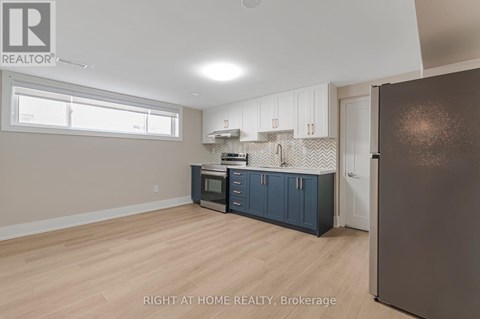 A kitchen with a refrigerator, cabinets, and a microwave.