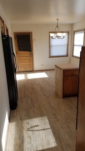A kitchen with a black refrigerator and wooden floors.