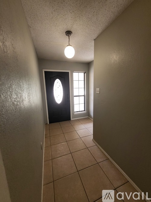A hallway with a light on and a door at the end.