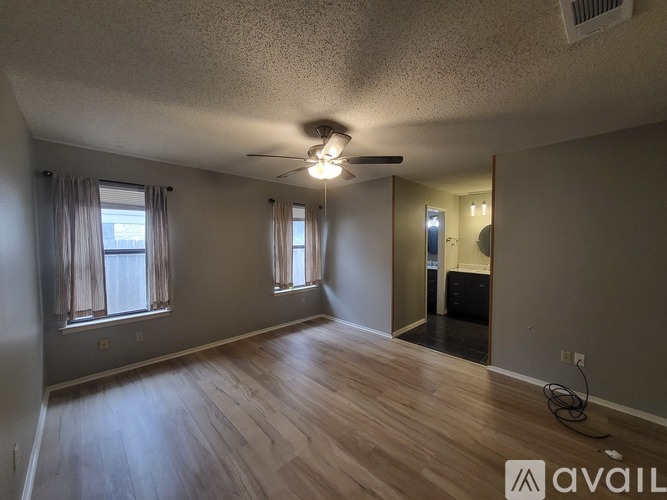 A spacious room with wooden floors and a ceiling fan.