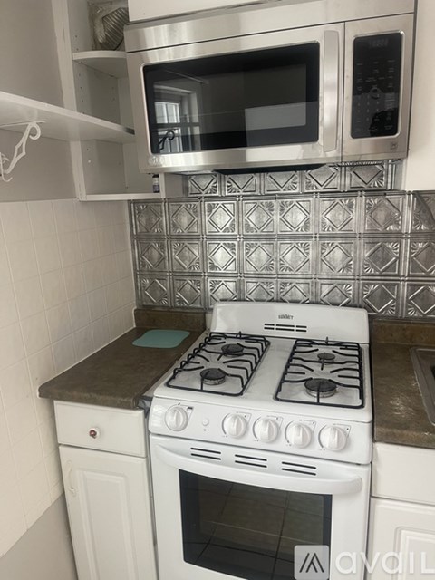 A kitchen with a white stove and a microwave above it.