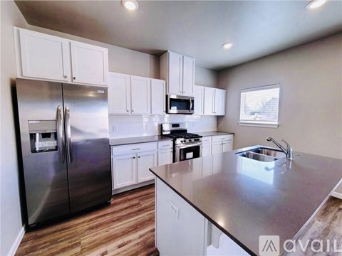 A kitchen with a stainless steel refrigerator, microwave, and stove.