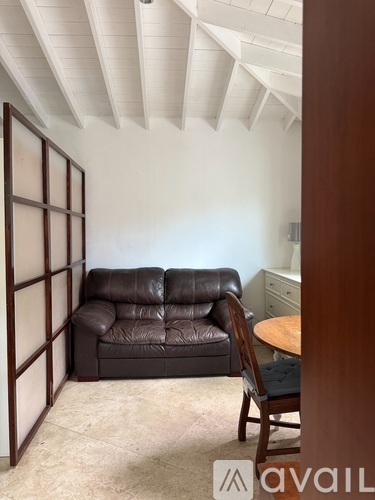 A living room with a brown leather couch and a wooden chair.