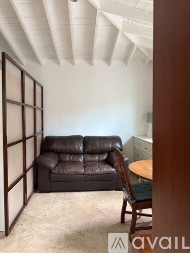 A living room with a brown leather couch and a wooden chair.