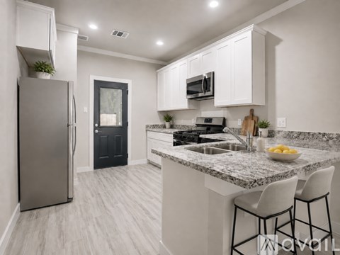 A modern kitchen with a granite countertop and white cabinets.