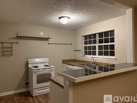 A kitchen with a white stove and a window with bars.