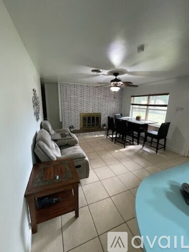 A living room with a sofa, chairs, and a ceiling fan.