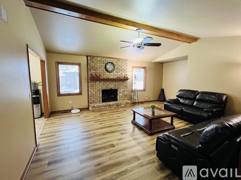 A living room with a black leather couch and a fireplace.