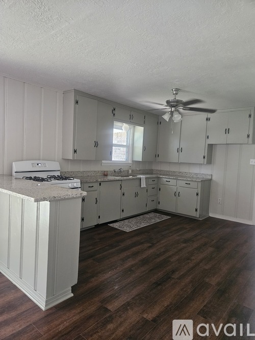 A kitchen with white cabinets and a wooden floor.