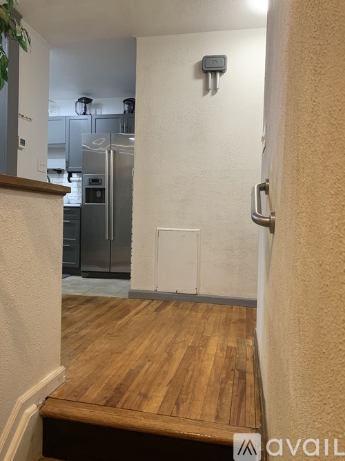 A kitchen with a refrigerator and wooden floors.