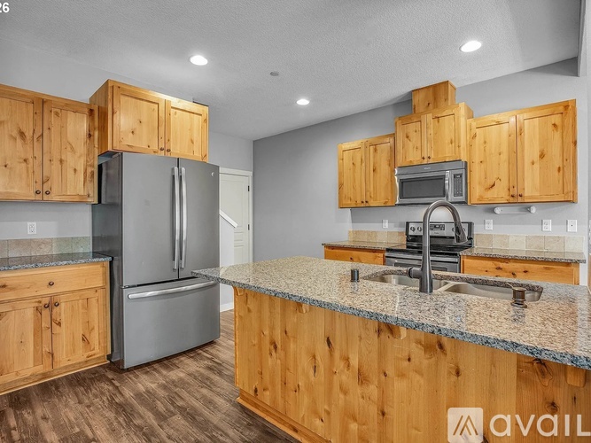 A kitchen with a black refrigerator, white fridge freezer, and wooden cabinets.