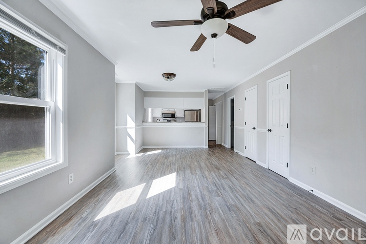 A spacious room with a ceiling fan and wooden flooring.