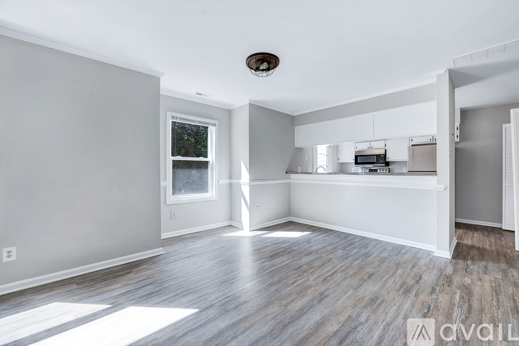 A spacious room with wooden flooring and a window on the left wall.