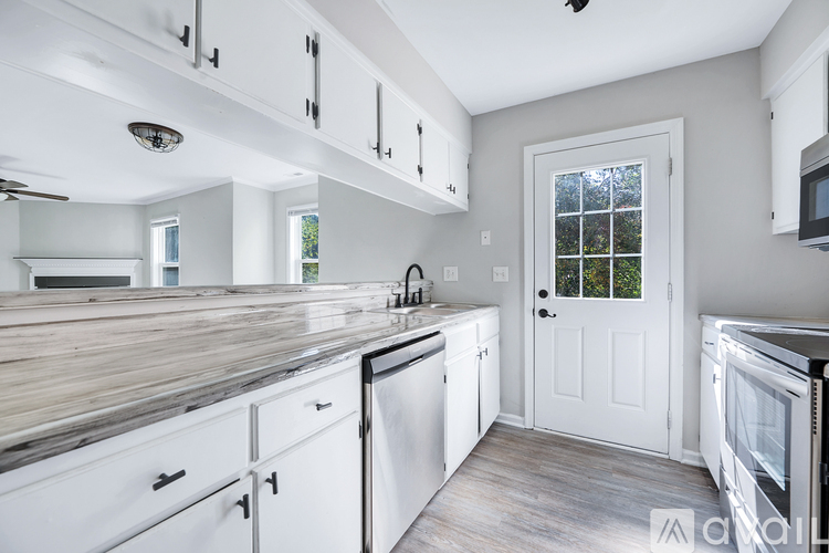 A kitchen with white cabinets and a wooden counter top.