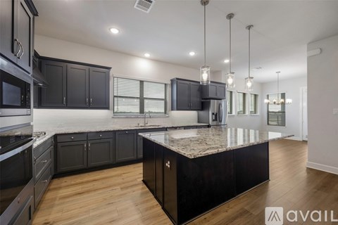 A modern kitchen with dark wood cabinets and a granite countertop.