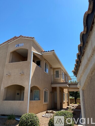 A tan stucco house with balconies and a small garden in front.
