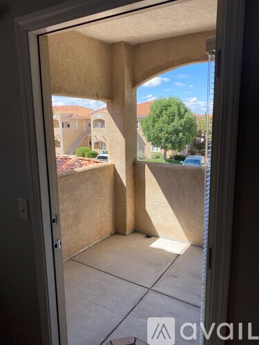 A view from inside a room looking out to a courtyard with a tree and buildings in the distance.