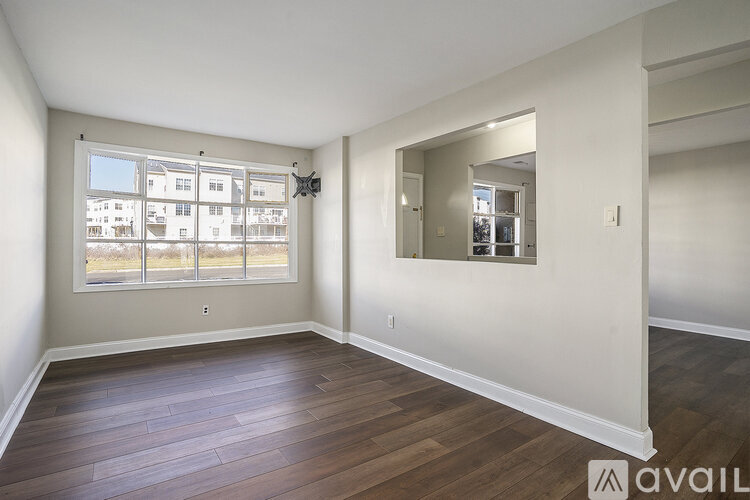 A spacious room with wooden floors and a large window.