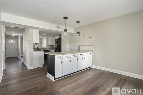 A kitchen with white cabinets and a wooden floor.