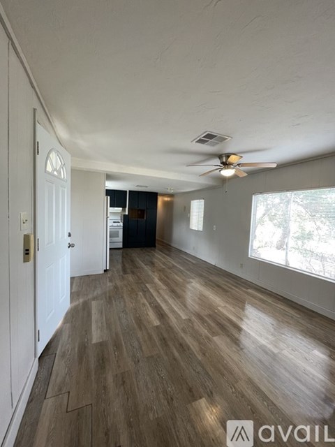 A spacious room with wooden flooring and a ceiling fan.